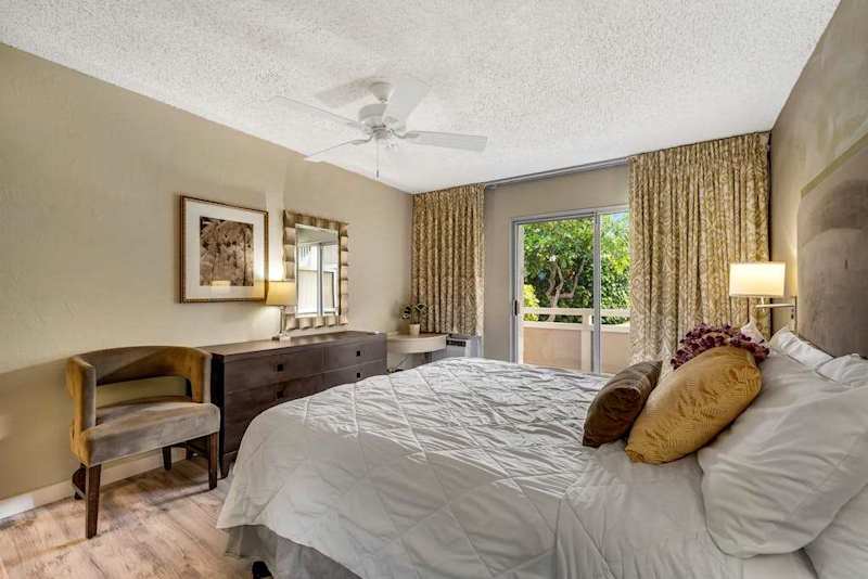 Alternate Angle of Primary Bedroom Highlighting Wooden Dresser, Accent Chair, and Balcony View
