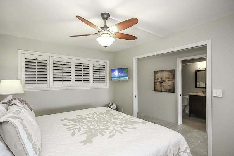 Master bathroom with king bed, flat screen tv and a ceiling fan.