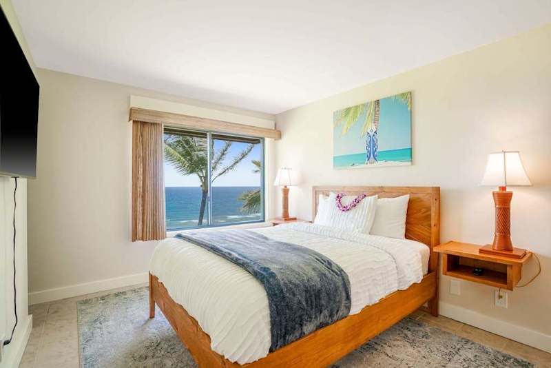 Cozy bedroom featuring a queen bed, warm lighting, and tropical ocean views