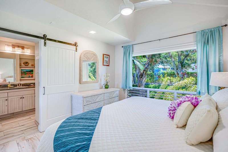 Bright primary bedroom with tropical décor and natural light.