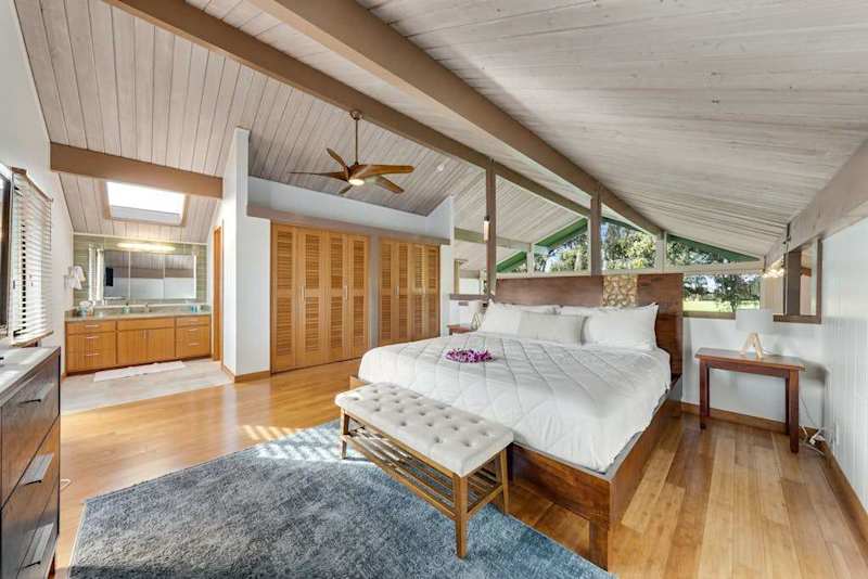 Bright bedroom seating pairs cozy bed views and overhead beams