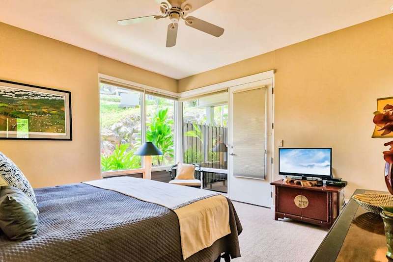 Master bedroom with king bed, flat screen tv and large windows for tropical views and private lanai access.