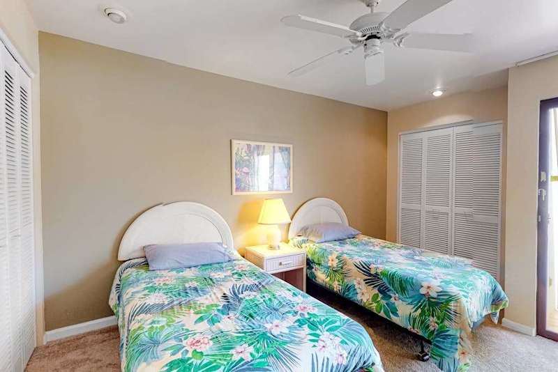 This bedroom features twin beds ceiling fan and natural light