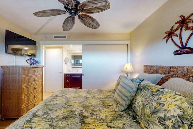 Primary bedroom with king bed, ceiling fan, en suite bathroom and a flat screen TV