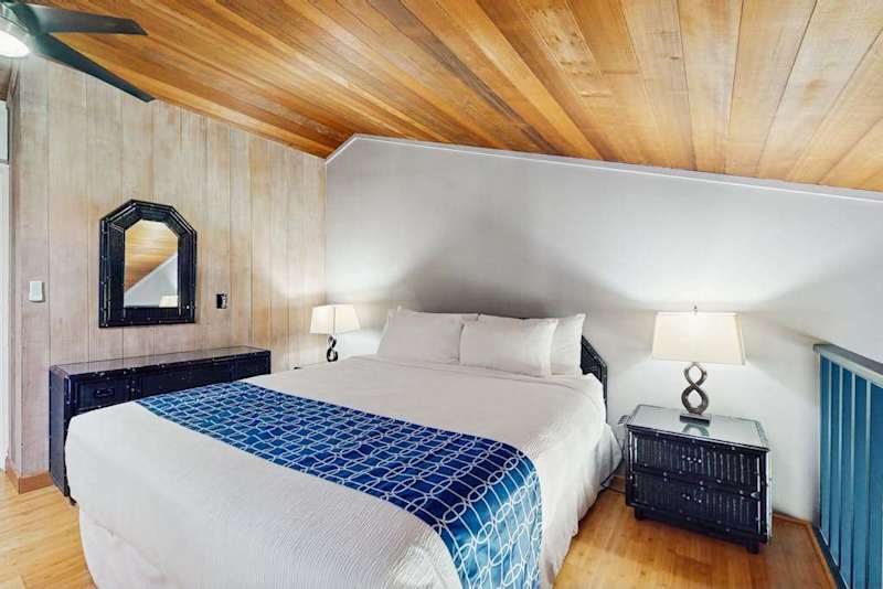 Cozy bedroom features comfortable bedding, wood ceilings, and bedside lamps
