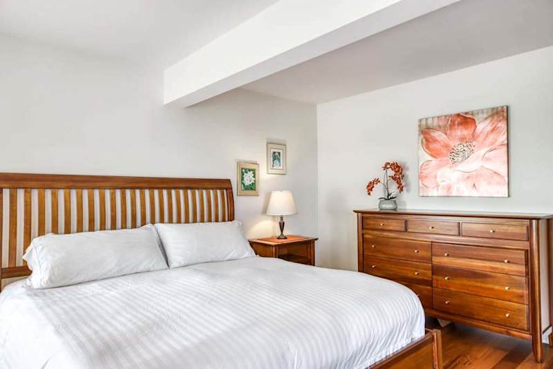 Well-Appointed Bedroom with King Bed, Matching Wooden Dresser, and Floral Wall Art