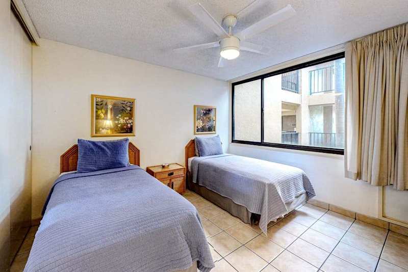 Two comfortable twin beds with a window overlooking the resort grounds