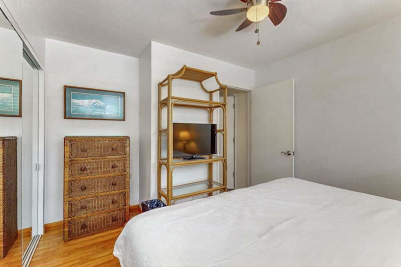 First bedroom shows bed, dresser, ceiling fan, shelving, and artwork
