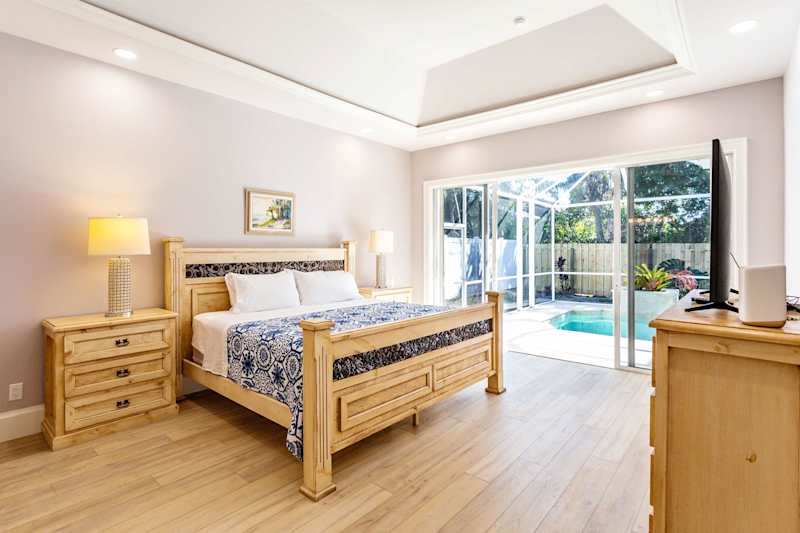 Master bedroom with king bed, tv and entrance to the pool