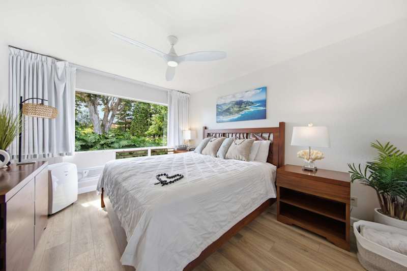Restful bedroom features layered bedding, calming artwork, and natural brightness