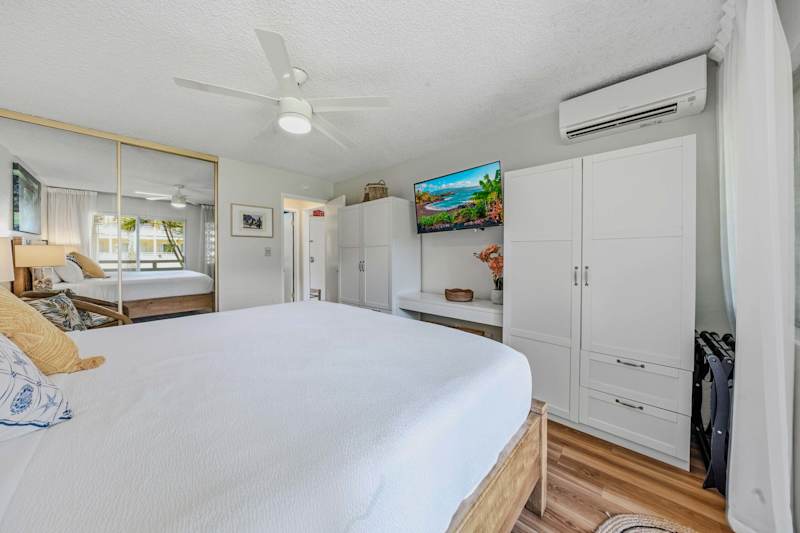 Bedroom view featuring king bed, white wardrobe, split A/C & wall-mounted TV