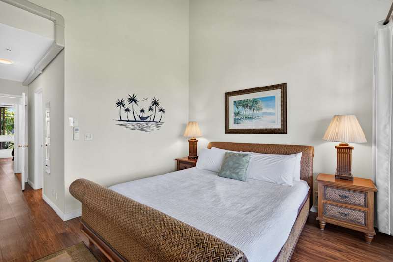 Primary bedroom featuring a king bed with woven frame and bedside lamps