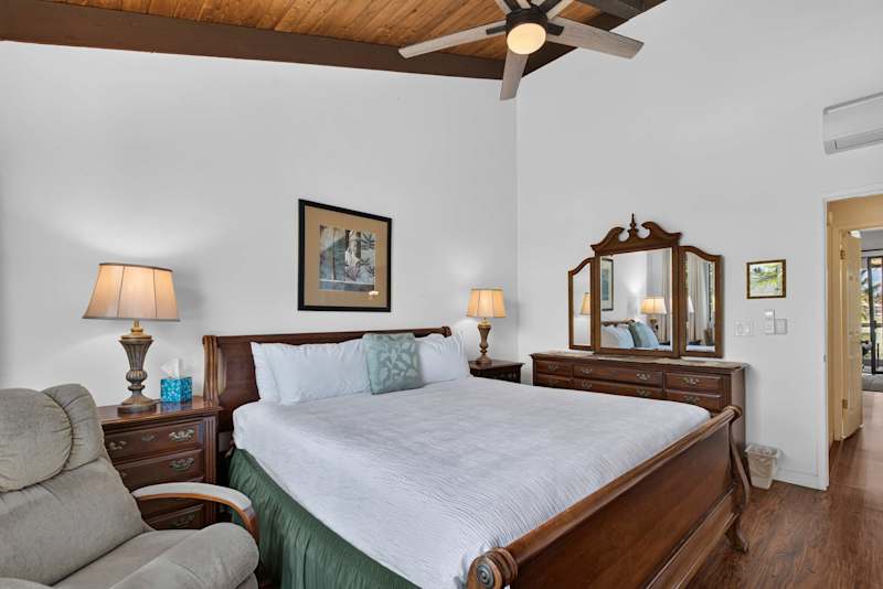 Primary bedroom featuring king bed, wooden vanity dresser, and ceiling fan