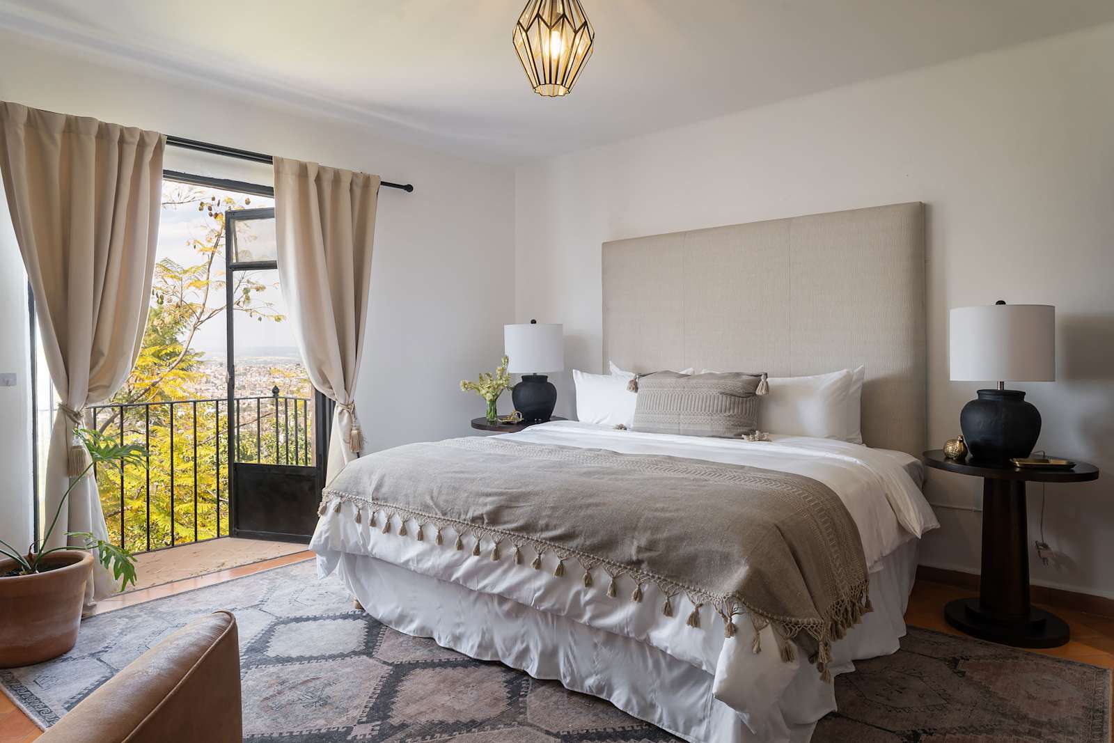 Bedroom with upholstered headboard, balcony access, and view of surrounding hillside