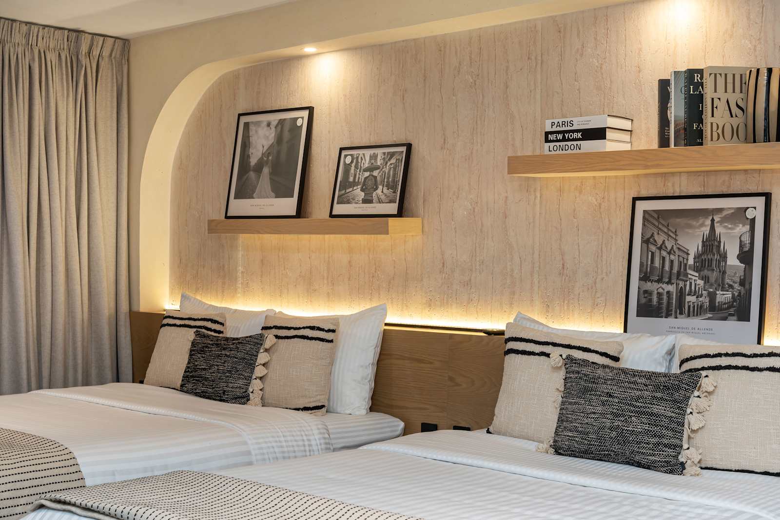 Bedroom with queen beds featuring an arched wood accent wall, framed art, and a TV console with wood built-in storage.