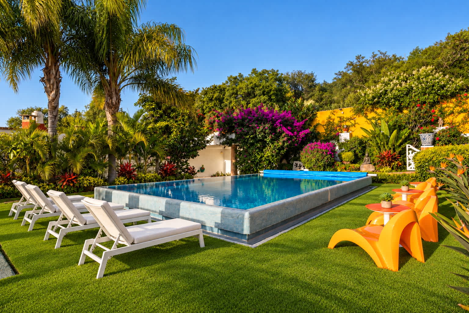 Pool and garden terrace with white lounge chairs, magenta bougainvillea, and palm trees