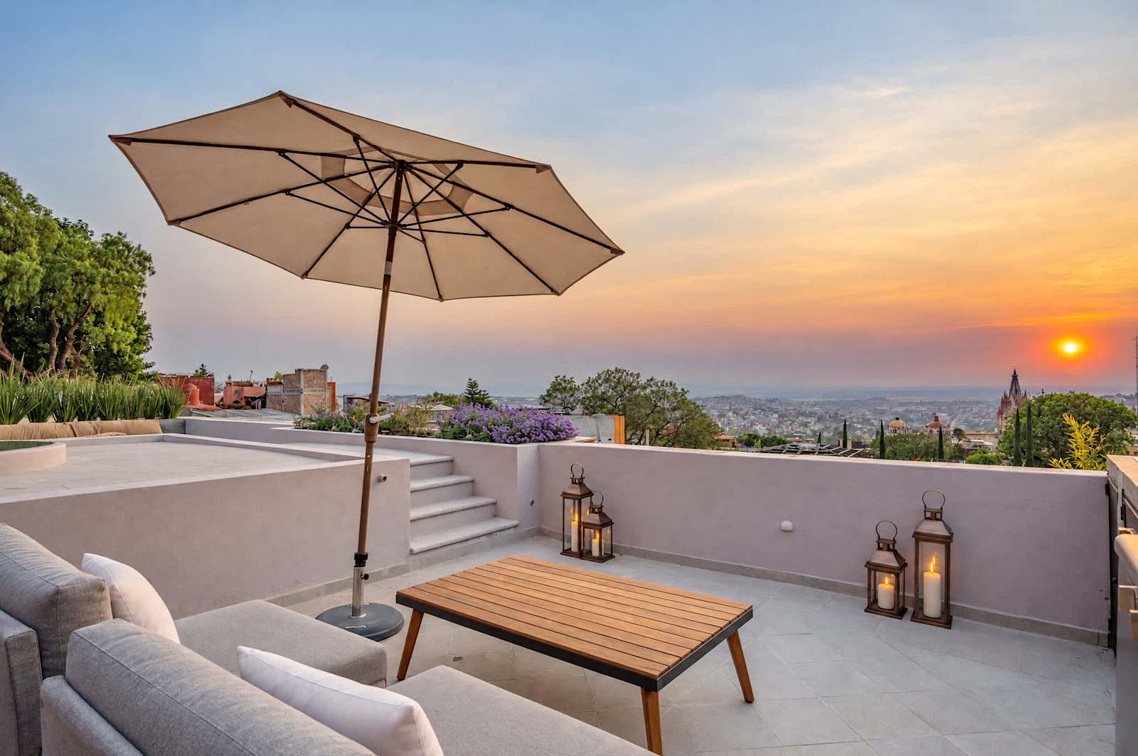 Azotea al atardecer con sombrilla, asientos y vista panorámica de San Miguel de Allende