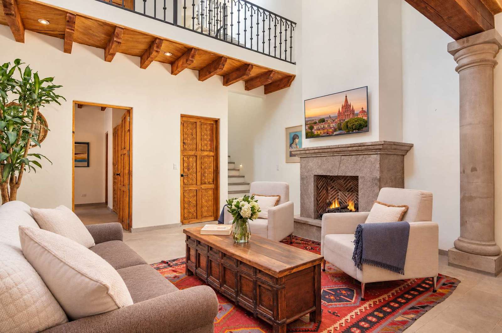 Sala con chimenea, vigas de madera, muebles cómodos y mezanine arriba