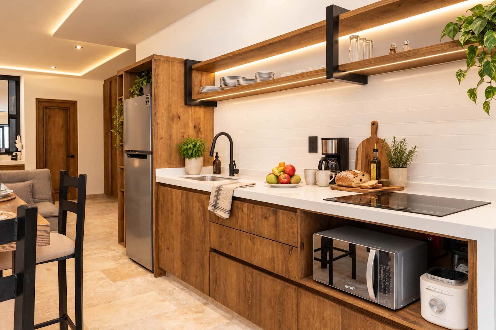 Cocina moderna con gabinetes de madera, azulejos blancos en la pared y repisa abierta sobre electrodomésticos de acero inoxidable