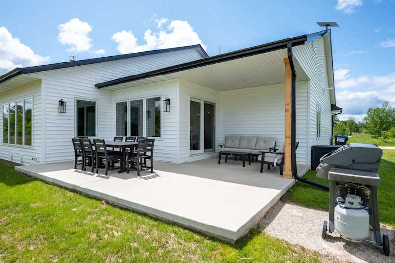 An outdoor dining set, BBQ grill, and comfortable seating area create the perfect space to unwind and enjoy fresh Door County air.