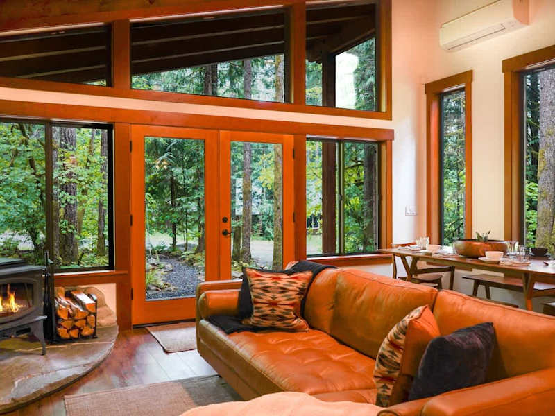 Living room facing out the floor to ceiling windows around the French doors with the fireplace in the corner. 
