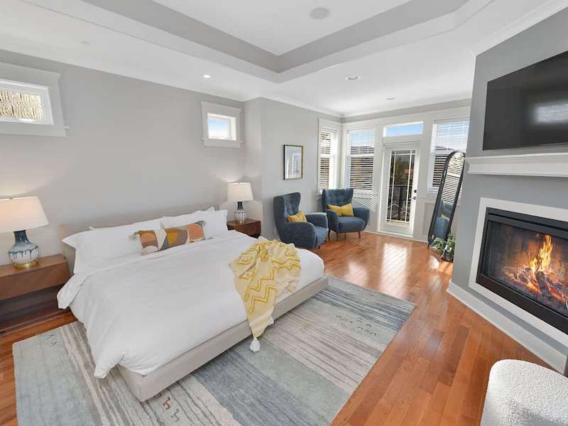 Primary bedroom king bed with private deck access and electric fireplace.