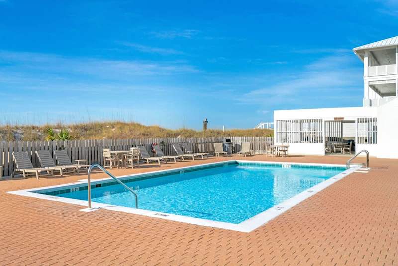 Outdoor community pool with clubhouse and charcoal grills.