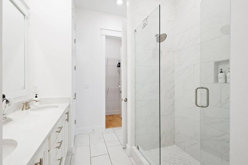 Bathroom features dual vanities and walk-in shower.