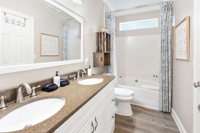 Bathroom feature dual vanities and a shower/tub combo.
