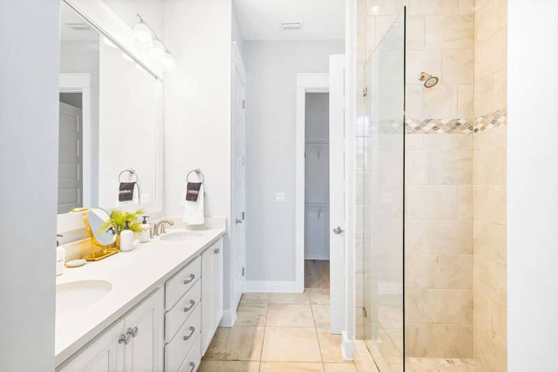Bathroom features dual vanities and walk-in shower.