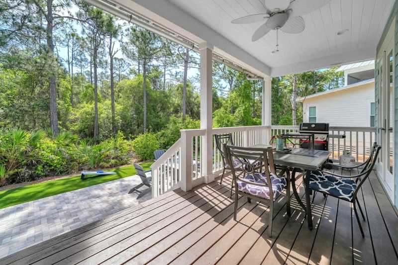 Covered porch off living room features seating and a gas grill.