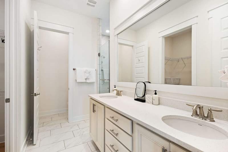 Bathroom features dual vanities and a walk-in shower.