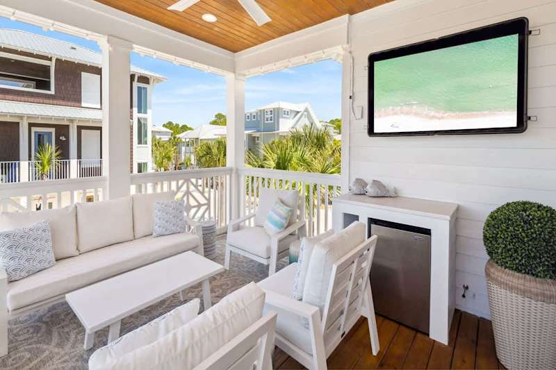 Covered balcony off second floor living area includes ample seating and a smart tv.