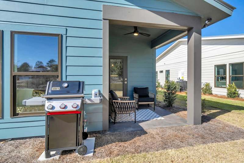 Back porch includes seating and a gas grill. Perfect for afternoon or evening cookouts.