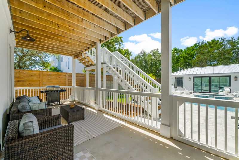 Outdoor covered porch with seating and gas grill.
