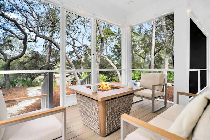 Private screened in porch with seating and firepit, perfect for morning coffee or winding down after a day at the beach.