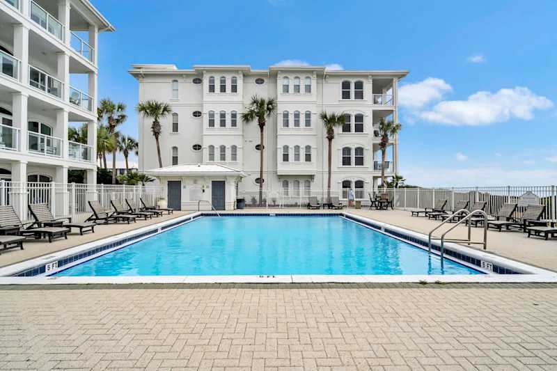 Beautiful community pool complete with sun loungers overlooks the emerald waters of the Gulf.