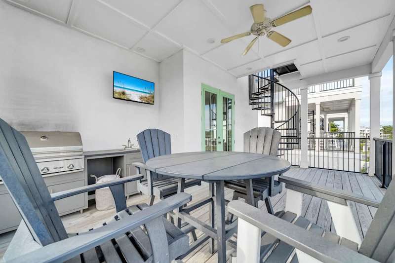 Covered outdoor seating with gas grill and tv.