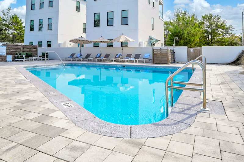 Heated community pool with sun loungers and outdoor seating.