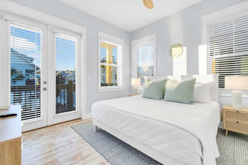 King bed in guest bedroom, with smart tv, walk-in closet, and access to private porch.