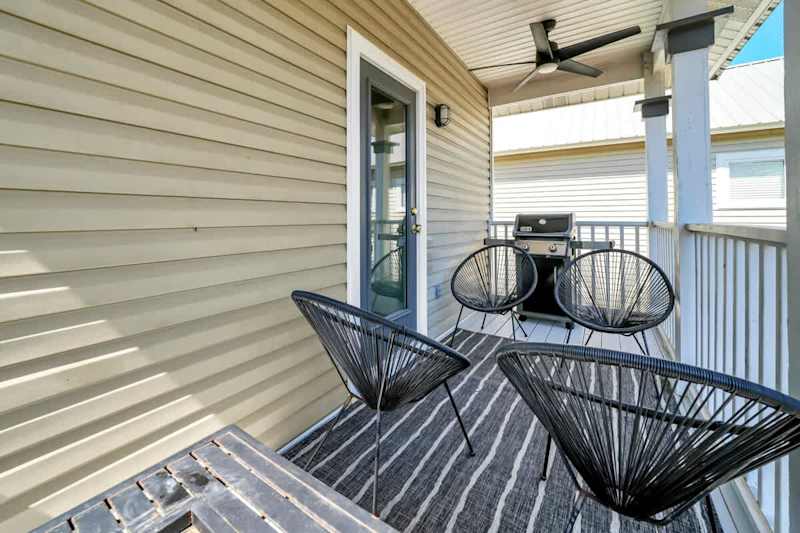 Second floor private covered porch with seating, gas grill, and fireplace