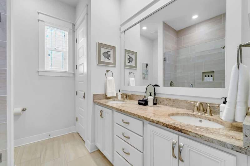 Bathroom features dual vanities and walk-in shower.