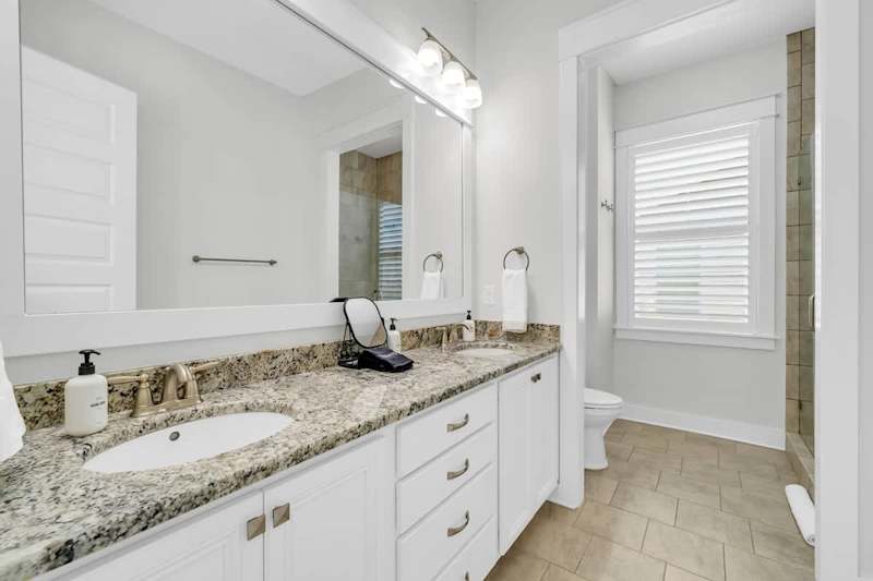 Bathroom features dual vanities and walk-in shower.
