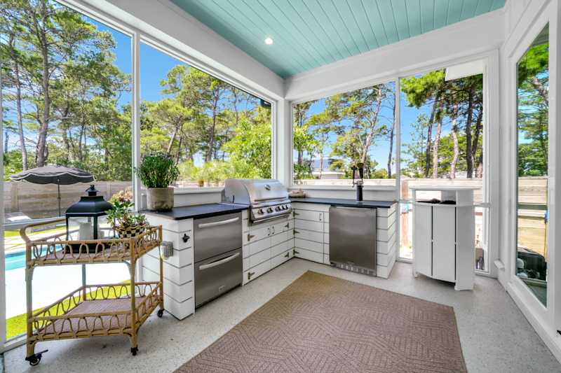 Screened in porch with outdoor seating, gas grill, fridge, and smart tv. 