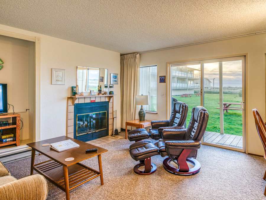 Living room with fireplace and ocean-facing window in Unit 01 at Hi-Tide Resort