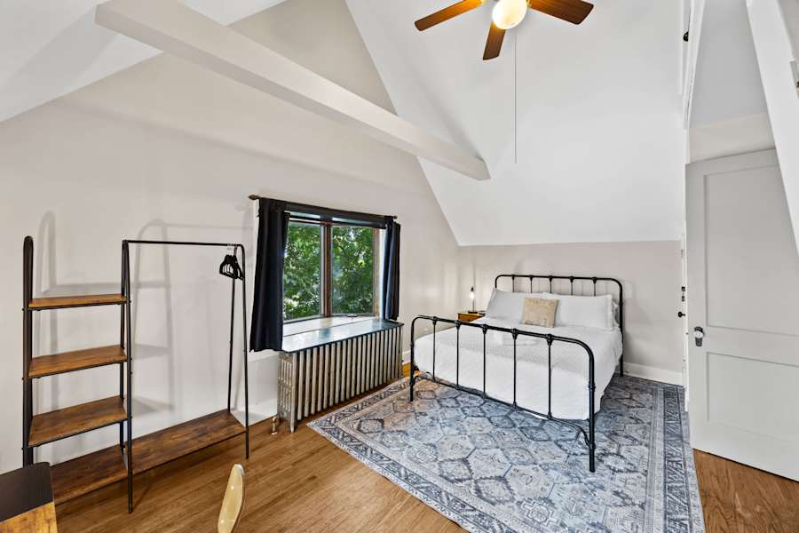 A bedroom in the second-floor apartment has a queen bed with plush pillows.